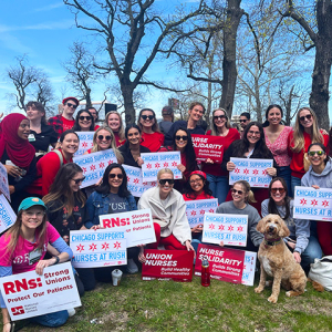 Large group of people outside, smiling, holding signs "Chicago Supports Nurses At RUSH"