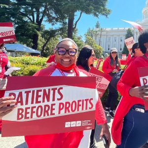 Nurses marching in Sacramento holding "Patients not profits," signs