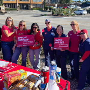Large group of nurses outside, picketing, with signs "Union nurses build healthy communities" 