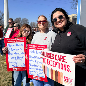Three nurses picketing outside hospital holding signs calling for better working conditions