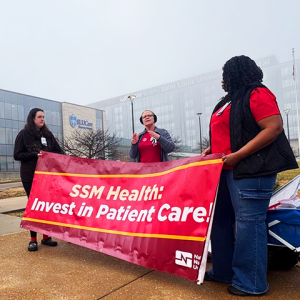 Nurses rallying with banner "SSM Health: Invest in Patient Care!" and sign "Staff up for safe care!"