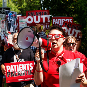 Marching folks with signs 'Palantir OUT!' and 'Patients over Palantir!"