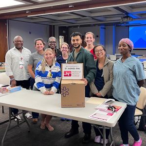 Group of nurses in conference room, behind ballot box, smiling