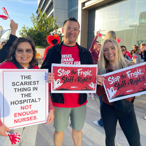 Three nurses outside smiling, holding signs "Stop the Fright, Staff it Right"