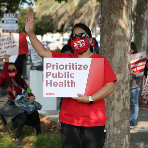 Nurse holds signs "Prioritize Public Health"