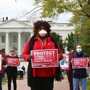 Nurses outside The White House hold signs "Protect Nurses, Patients, Public Health"