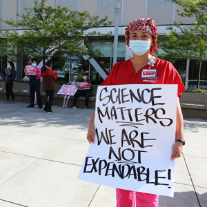Nurse holding sign "Science matters, we are not expendable!"