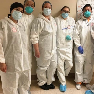 Group of five nurses inside hospital wearing protective gowns