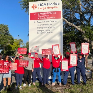 Large group of nurses outside HCA Florida Largo Hospital hold signs calling for safe staffing and other protections