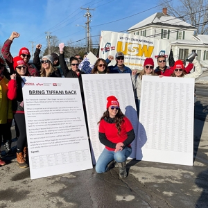 Group of nurses outside holding huge petition with signatures