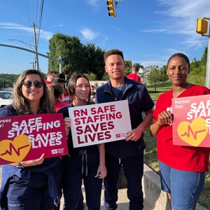 Four nurses outside holding signs "Safe Staffing Saves Lives"