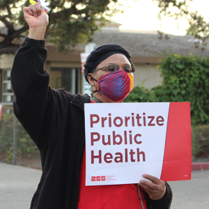 Nurse holds signs "Prioritize Public Health"