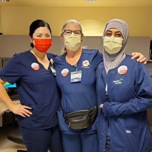Three nurses inside hospital with arms around each other