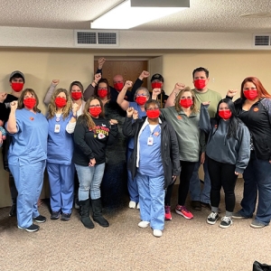 Large group of nurses inside hospital with raised fists