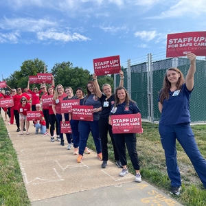 Long line of nurses holdings signs "Staff Up for Safe Patient Care"