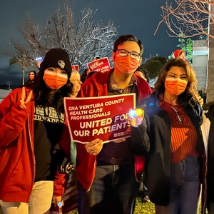 Three nurses standing outside, one holds sign "CNA Ventura County health care proffessionals united for our patients"