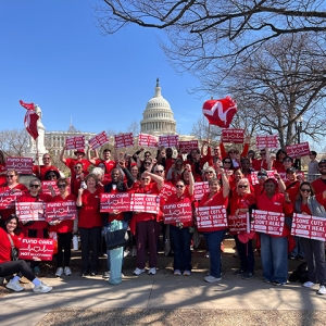 Large group of nurses outside Capitol building in Washington, D.C., holding signs "Fun Care, Not Billionaires" and "Some Cuts Don't Heal"