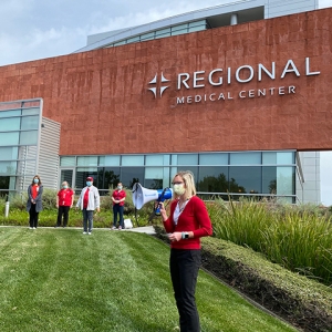 Speaker and nurses in front of Regional Medical Center building