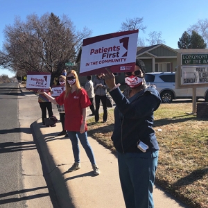 Group of four nurses outside Longmont Hospital hold signs "Patients First"