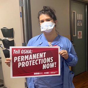 Nurse inside hospital hold signs calling for permanent ETS and safe staffing