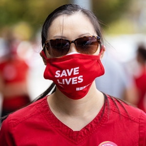Nurse in sunglasses wearing mask which says "Save lives"