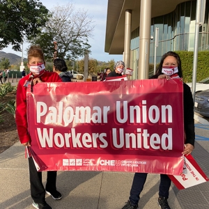 Two people outside hold sign "Palomar Union Workers United"