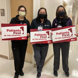 Three nurses inside hospital hold signs "Patients First"