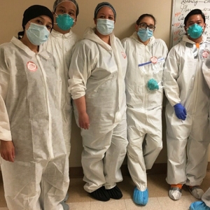 Group of five masked nurses inside hospital