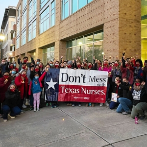 Large group of nurses outside hold sign "Don't mess with Texas nurses"