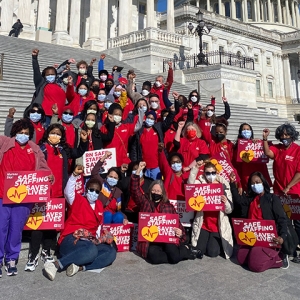 Nurses outside Capitol building with raised fists holding signs "Safe Staffing Saves Lives"