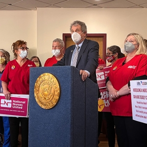 U.S. Senator Sherrod Brown at podium with nurses by his side