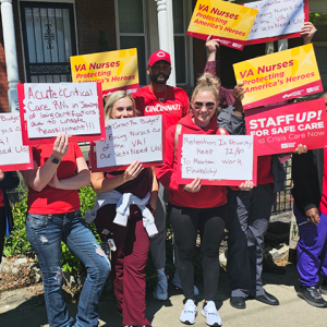 Group of VA nurses smiling, lots of diferent signs including "VA Nurses: Protecting America's Heroes"