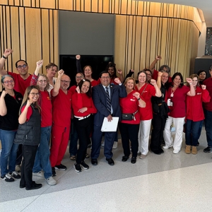 Large group of nurses with Sen. Arreguín inside, smiling, raised fists