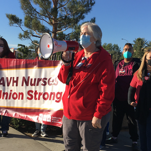 AVH RN speaks using megaphone in front of sign "AVH Nurses - Union Strong"