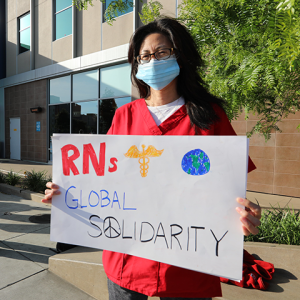 Nurse holds signs "RNs Global Solidarity"