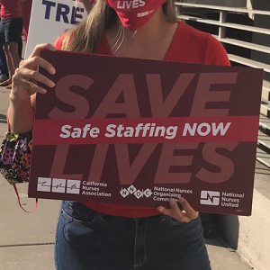 Nurse holds signs "Safe Staffing Now"