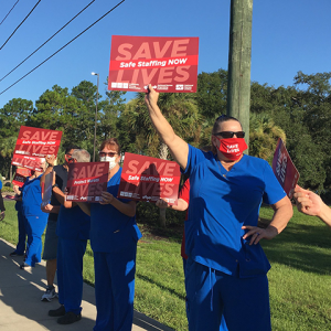 Nurses hold signs "Safe Staffing Now"
