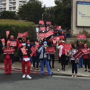 RNs on the street in front of hospital holding signs "Save Lives'
