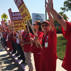 Nurses outside Hazel Hawkins Hospital hold signs "Some cuts don't heal"