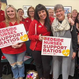 Group of smiling nurses holding signs "Bedside Nurses Support Ratios"