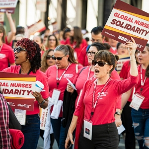 Nurses marching, holding signs "Global Nurses Solidarity"