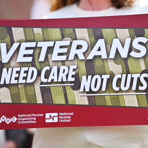 Nurse holding sign "Veterans need care not cuts"