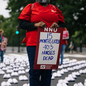 Nurse holds sign "15 months later, 403 nurses dead"