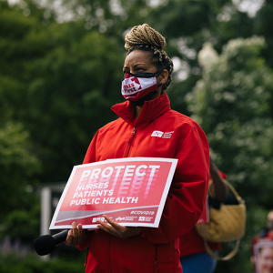 Nurse holds sign "Protect Nurses, Patients, Public Health"