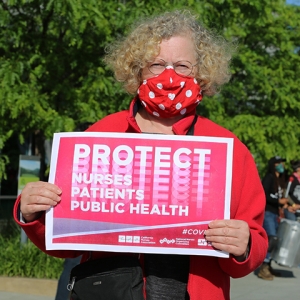 Nurse holding sign "Protect Nurses, Patients, Public Health"