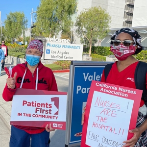 Group of three nurses outside LA Medical Center hold signs "Patients First"