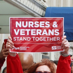 Nurse holds sign "Nurses & Veterans Stand Together"