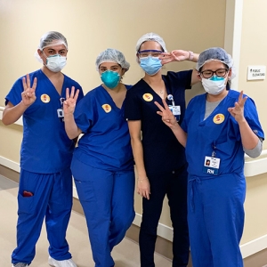 Four nurses inside hospital holding up three fingers