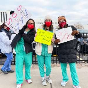 Three nurses outside holding signs "Save Our Staff", "Fair Contract Now", "Fair Bargaining"