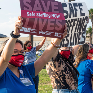 Corpus Christi nurses holding signs on street "Save lives: Safe staffing now" and "Safe staffing saves lives"